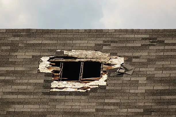 Large hole in shingled roof, for themes of security, insurance, repair