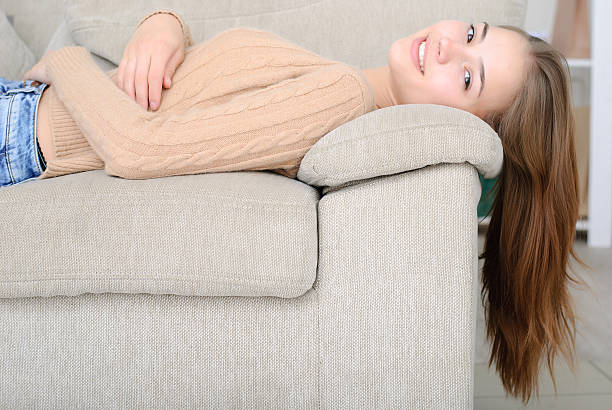 istock smiling young woman lying on couch 611901526