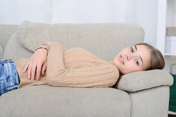 istock smiling young woman lying on couch 611901686