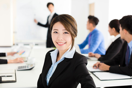 Smiling businesswoman looking at camera with  colleague in meeting