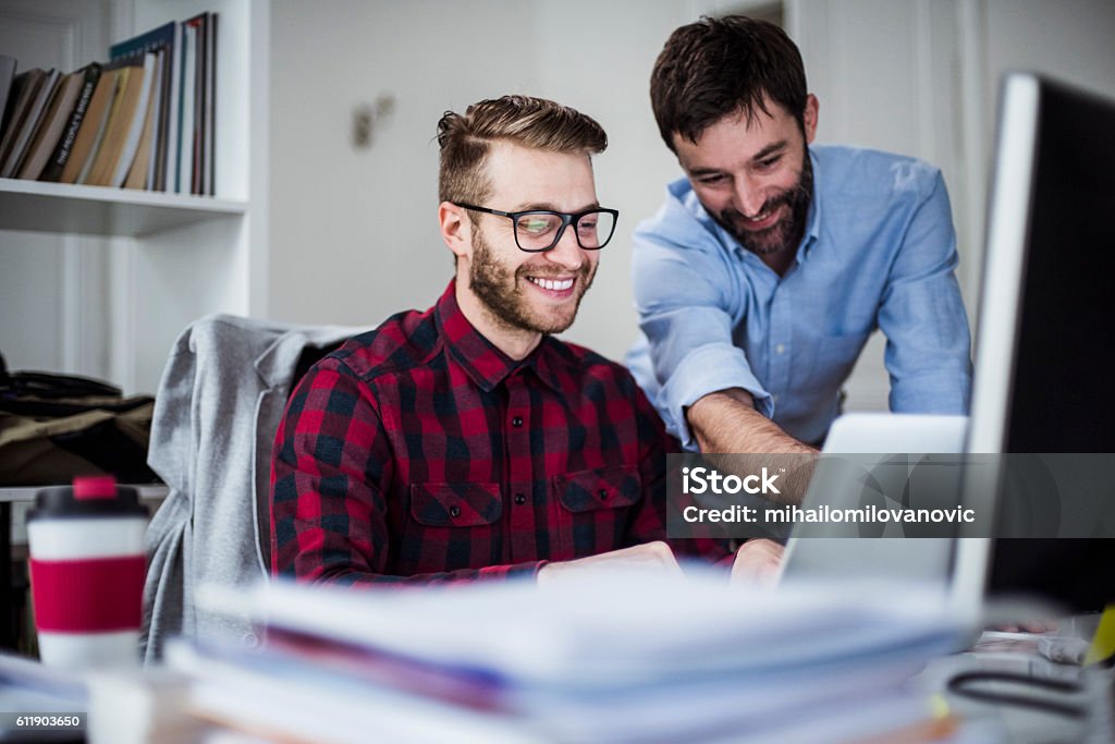 Two happy men in the office Two happy men working in the office Trainee Stock Photo