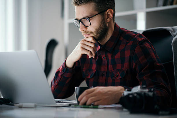 Young entrepreneur working on a new project Young man drinking coffee while working on a laptop at office asking yourself stock pictures, royalty-free photos & images