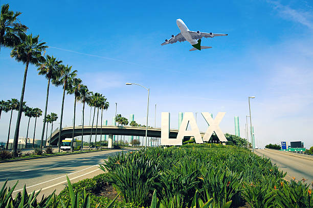 Los Angeles Airport LAX Los Angeles Airport sign full highway with airplane flying overhead. economy class stock pictures, royalty-free photos & images
