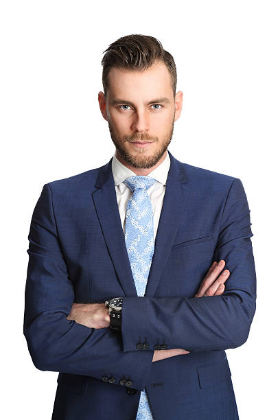 Handsome businessman in blue Attractive businessman standing with his arms crossed wearing a blue suit, white shirt and light blue tie looking at camera. White background. vibrant color lifestyles vertical close up stock pictures, royalty-free photos & images