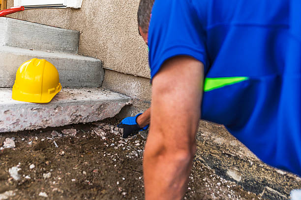 istock Construction worker examining settlement of home foundation under removed patio 611993522