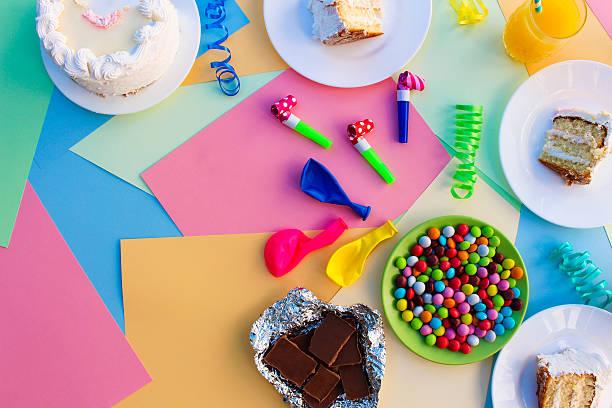 Cake, candy, chocolate, whistles, streamers, balloons, juice on holiday table