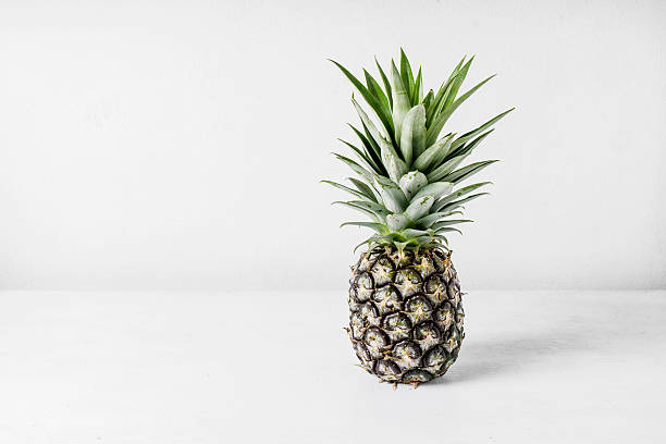 istock Pineapple on wooden table over white background 612002286