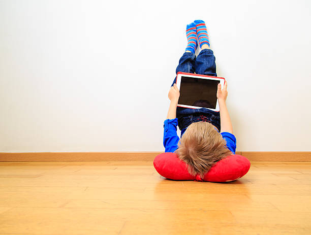 istock little boy looking at touch pad indoors 612003538