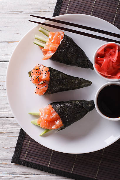 istock Salmon temaki sushi, pickled ginger and sauce closeup. vertical 612003966