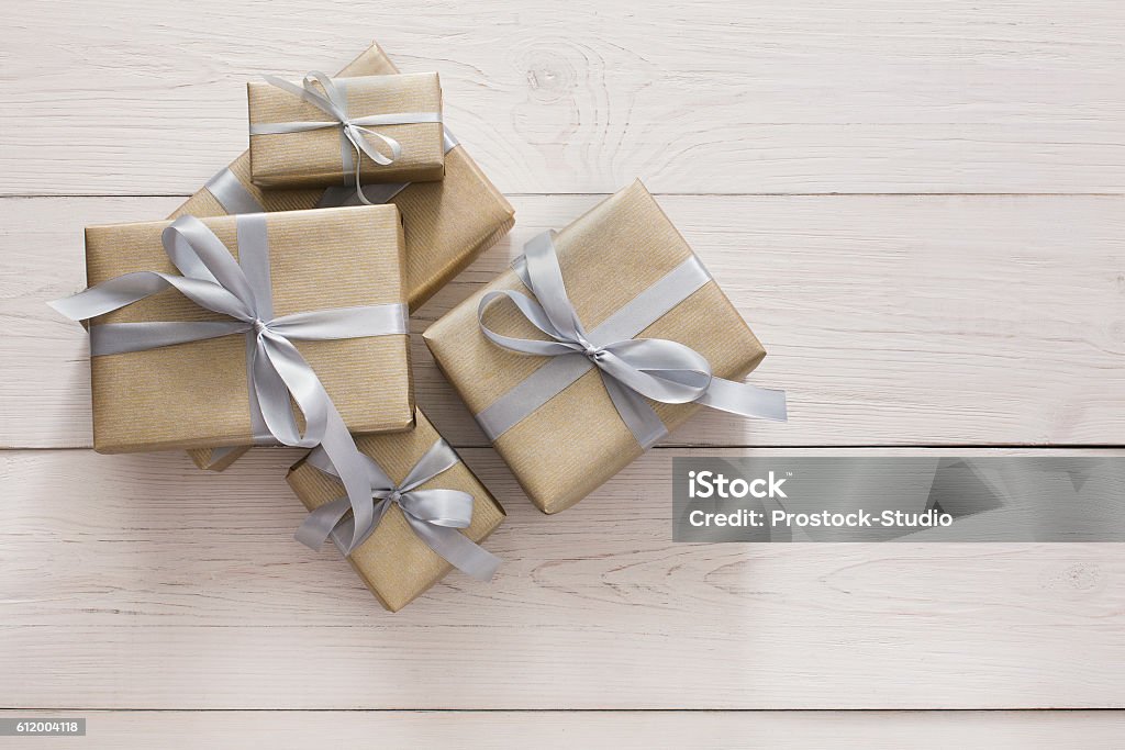 Top view of present boxes on white with copy space Top view of Gift boxes on white wood background. Presents in craft paper decorated with stylish elegant silver satin ribbon bows. Christmas and any other holidays concept, above view with copy space. Ribbon - Sewing Item Stock Photo