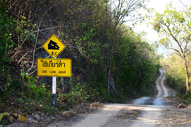 istock Downhill dust road with thai road sign 612013296