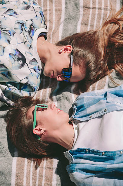 istock Women friends with sunglasses looking each other lying 612013618