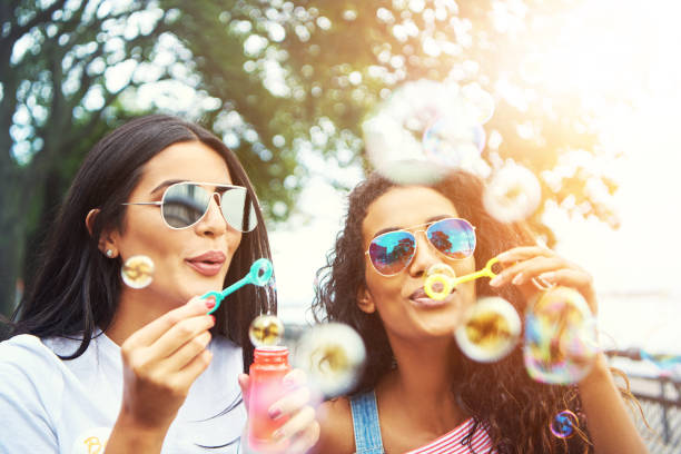 istock Female friends with sunglasses blow bubbles 612015158