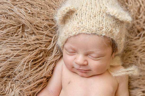 istock asleep smiling newborn baby in hat 612015354
