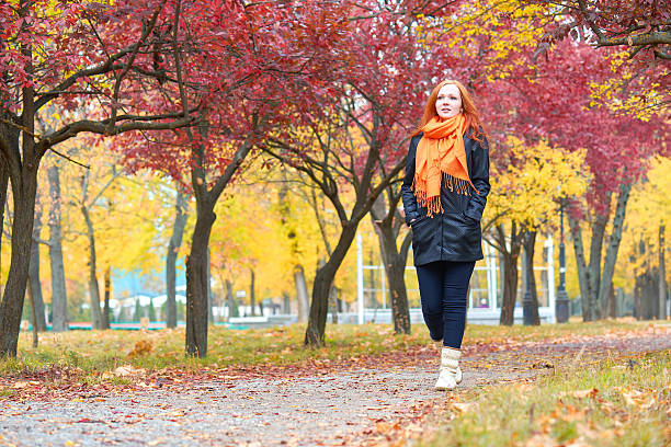 istock girl walk on pathway in city park with red trees 612015698