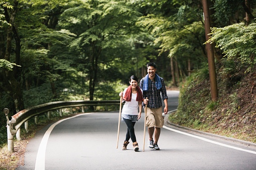 In this rural area of Kyoto, Japan, these two Asian hikers are having a blast, enjoying the nature and the company of each other. They have hiked a long way through the woods, carrying hiking poles and a backpack they were prepared for anything to come.
