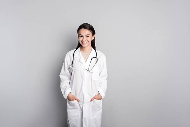 istock Positive female doctor standing against grey background 612022110