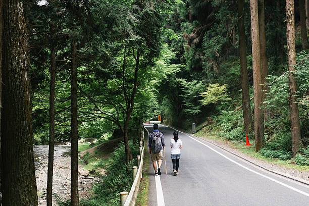 istock Asian Couple Walking down a Road in a Forest 612022776