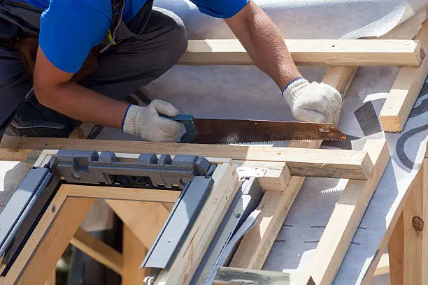 Photo of Roofer builder worker use saw to cut a wooden beam