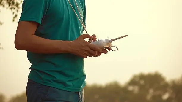 Photo of Man using drone RC remote at sunset