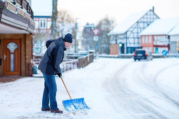 istock Man with snow shovel cleans sidewalks in winter 612030312