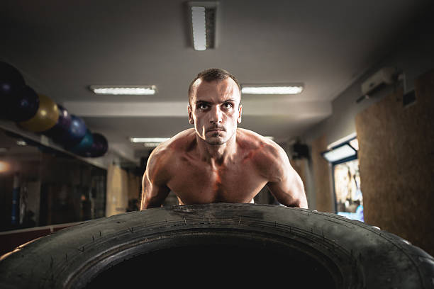 istock Man pushing tire in gym 612031374