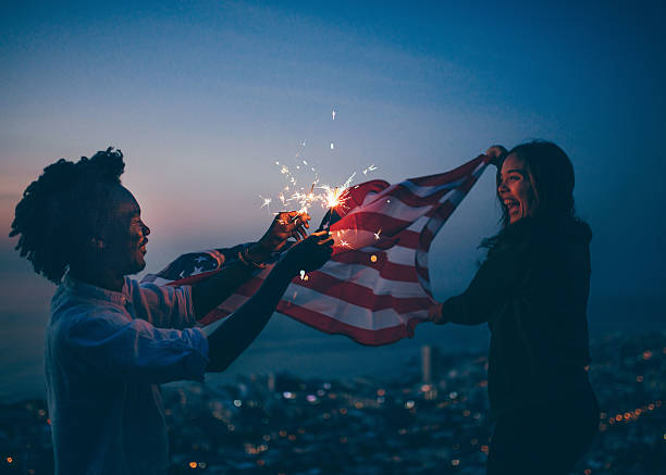 homme et femme afro-amerciens célébrant avec le drapeau des états-unis et - firework display celebration party fourth of july photos et images de collection