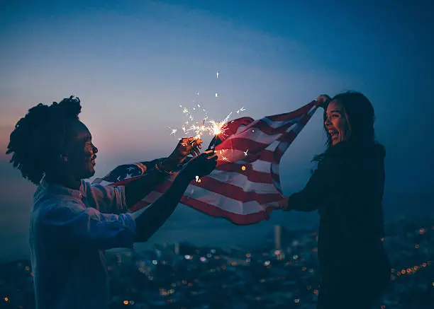 Photo of Afro amercian man and woman celebrating with USA flag and
