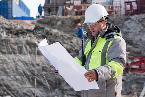 Civil Engineer At Construction Site Civil Engineer at construction site is inspecting ongoing production according to design drawings. civil engineer stock pictures, royalty-free photos & images