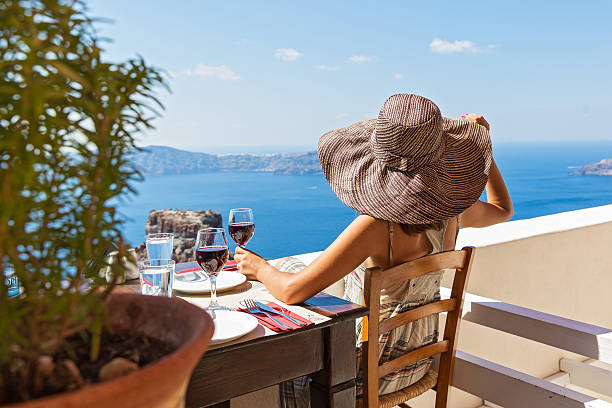 Young beautiful woman drinking red wine Young beautiful woman drinking red wine and watching the volcano of Santorini santorin stock pictures, royalty-free photos & images