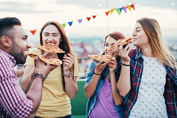 istock Young people eating pizza on a rooftop party 612227518