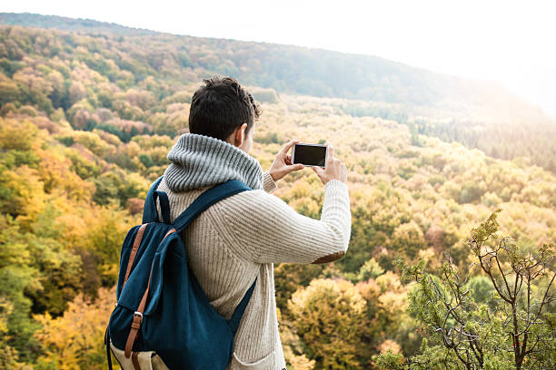istock Unrecognizable man with smart phone against colorful autumn fore 612229060