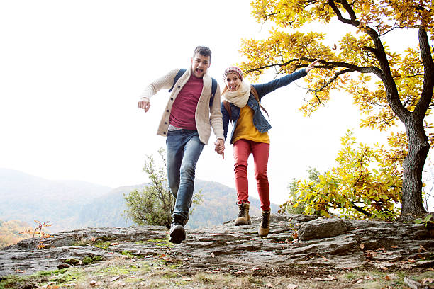 bella coppia nella soleggiata natura autunnale, che corre su una roccia - jogging autumn young women women foto e immagini stock