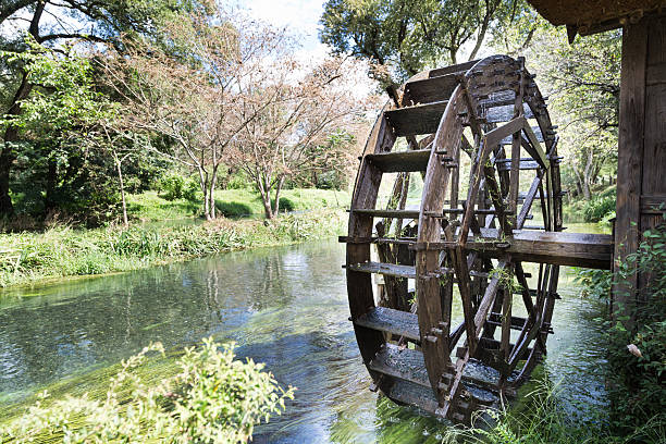 Ancient water wheel within serene and scenic river Ancient water wheel within serene and scenic river setting watermill stock pictures, royalty-free photos & images