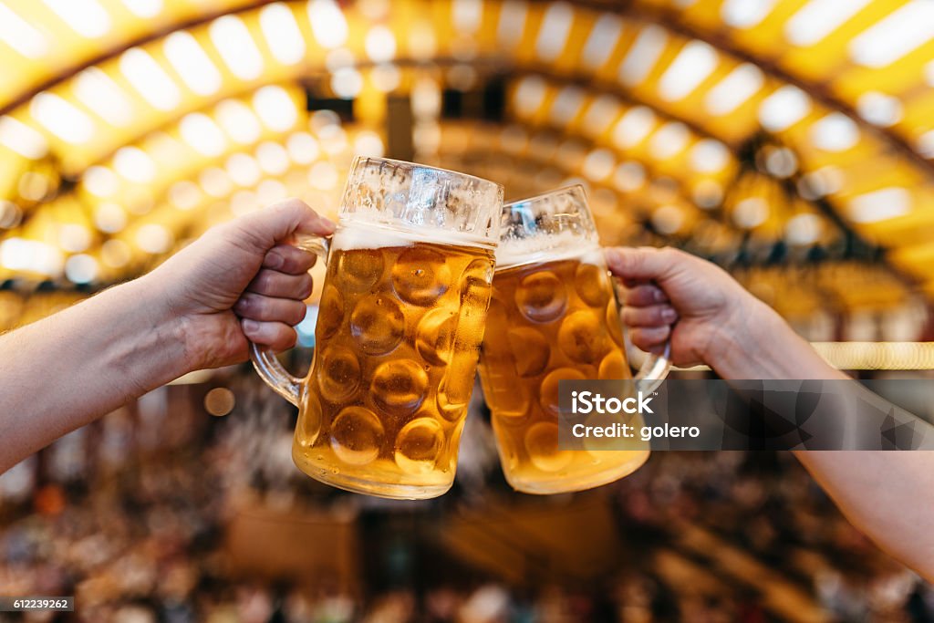 due mani clinking bicchieri di birra in octoberfest tendone - Foto stock royalty-free di Birra