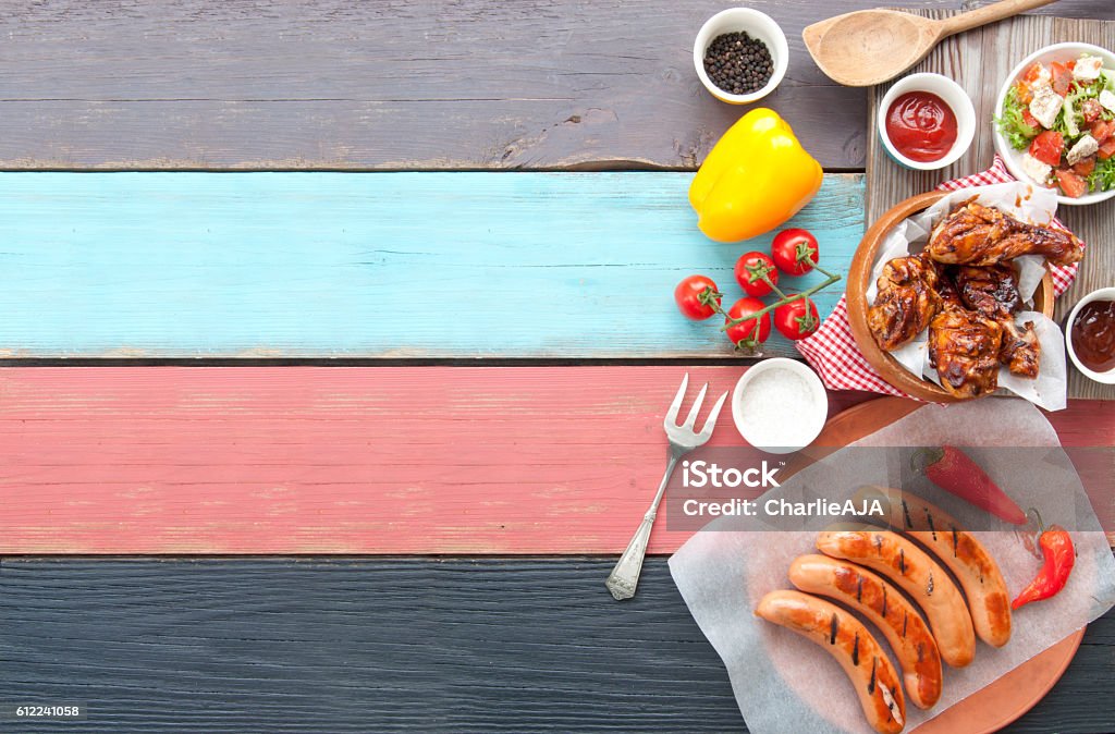 Barbecue meal background Selection of grilled barbecue meat including chicken and sausages with salad on top of a wooden table Grilled Stock Photo