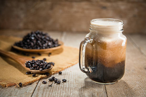 Nitro coffee fresh pour tap rustic lifestyle espresso mocha beans Fresh from the tap nitrous infused dark rich nitro black coffee in a glass jar java creamy beautiful froth foam head lifestyle decor with roasted beans on a rustic reclaimed wood wooden table background nitrogen stock pictures, royalty-free photos & images
