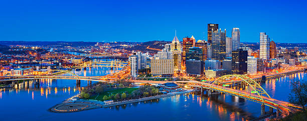 Downtown Pittsburgh Pennsylvania USA Panoramic cityscape photo of downtown Pittsburgh, Pennsylvania, USA, illuminated at twilight blue hour. It is located at the confluence of the Allegheny and Monongahela rivers. blue hour twilight photos stock pictures, royalty-free photos & images