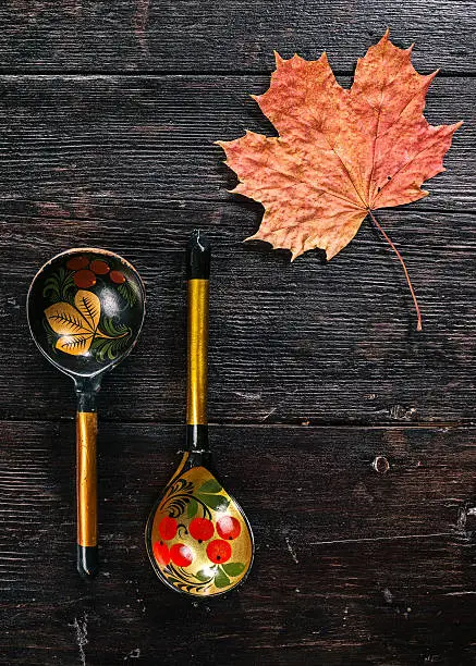Still life with Russian traditional painted spoons and maple leaf on the dark wood. Flat lay