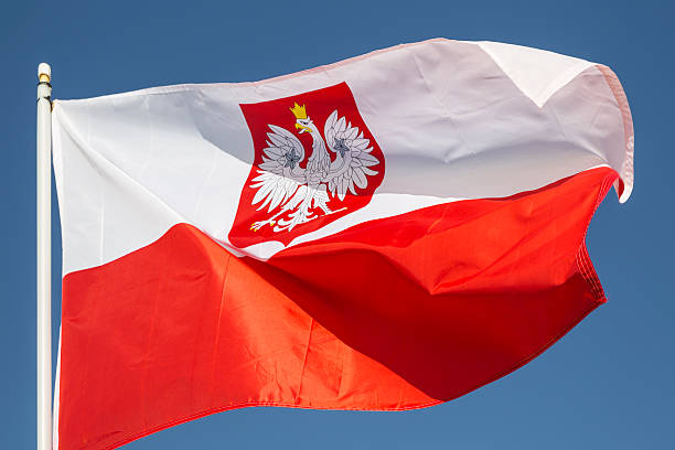 A closeup of the red and white flag of Poland flying in a stiff wind.  This flag is a variant of the usual red and white Polish flag with the national coat of arms in the middle of the white stripe.  It is normally reserved for official use abroad and at sea.