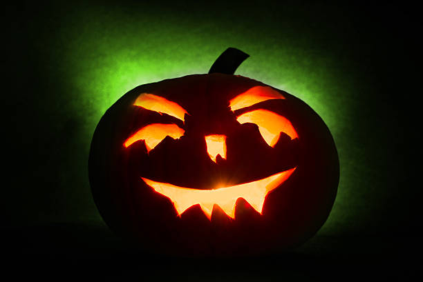 istock Halloween pumpkin  with burning candles on green background 612246184