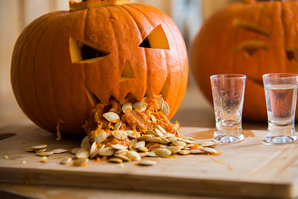 Pumpkin puking with pumpkin seeds on wood table, vodka Pumpkin puking with pumpkin seeds on wood table, vodka throwing up pumpkin stock pictures, royalty-free photos & images