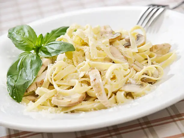 Pasta fettuccine alfredo with chicken, parmesan and parsley on blue wood background close up. Italian cuisine.