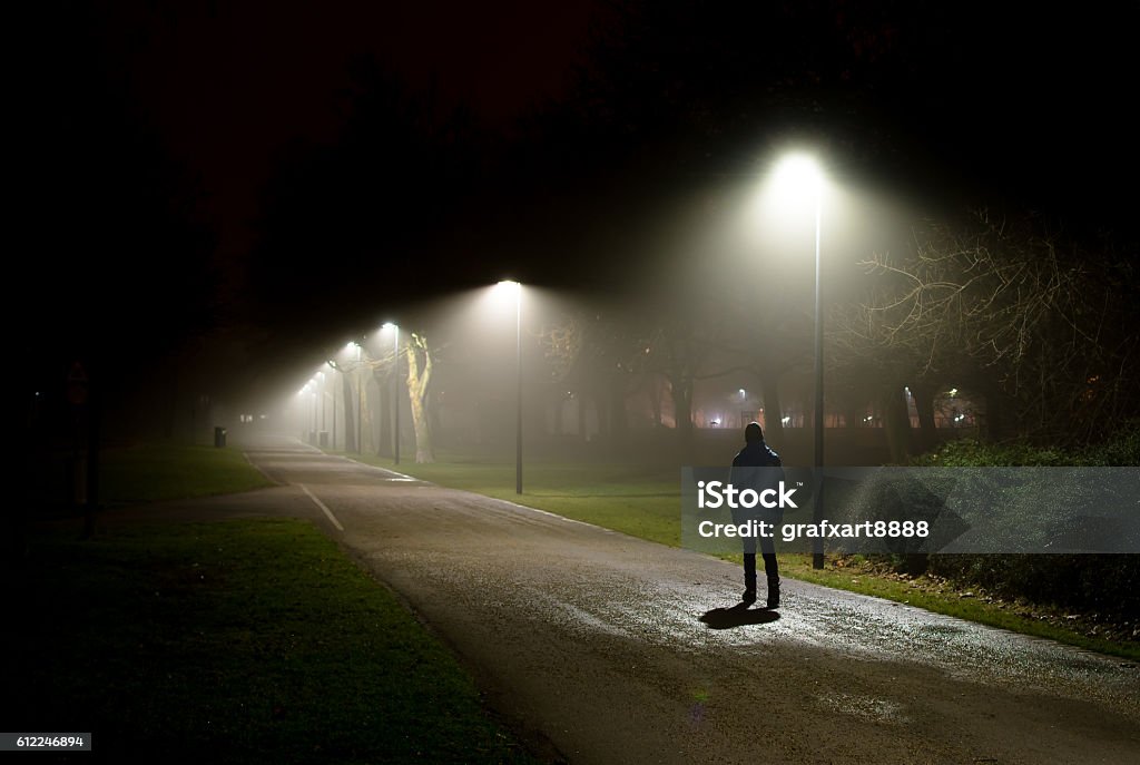 Una sola persona caminando por la calle en la noche oscura - Foto de stock de Noche libre de derechos