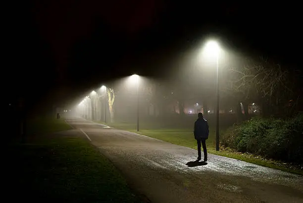 Photo of Single Person Walking on Street in the Dark Night