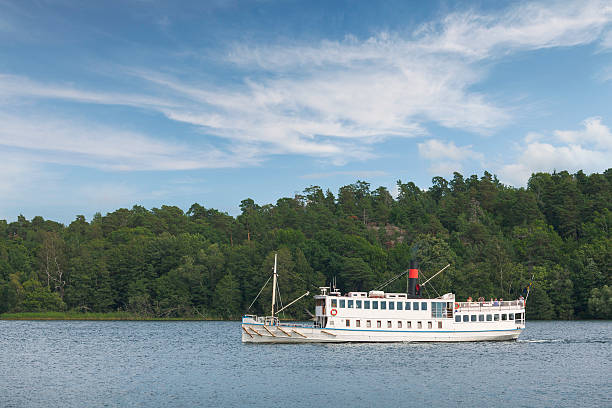 A boat is traveling on a calm body of water. The sky is a mix of blue and orange, creating a serene and peaceful atmosphere