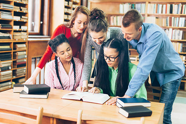istock Group of young people studying at the library together 612251982