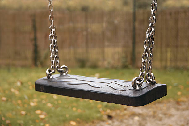 istock empty children swing on chains in an autumnal garden 612252250