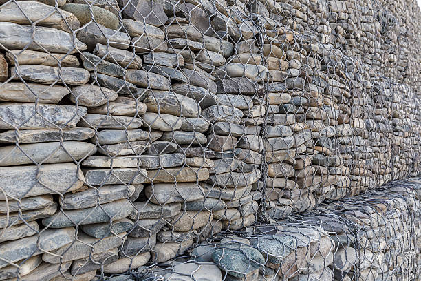 le mur de pierres de rivière emballé dans une grille métallique - pebble water gray silver photos et images de collection