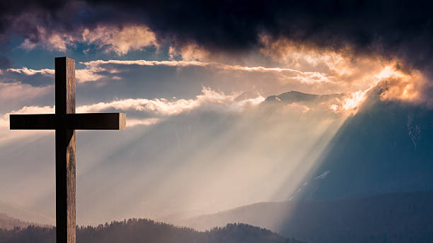 Jesus Christ wooden cross on a dramatic, colorful sunset     Jesus Christ cross. Christian wooden cross on a background with dramatic lighting, colorful sunset, twilight and orange -  purple clouds and sky.  Easter, resurrection,Good Friday concept holy week photos stock pictures, royalty-free photos & images